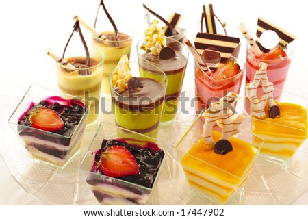 An assortment of colorful mousse desserts in cups, on a white background.