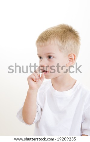 An adorable three year old picking his nose on white background.