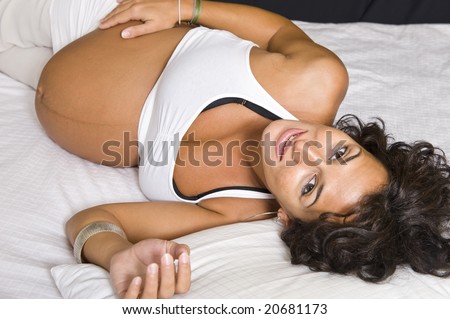 A beautiful pregnant girl showing her tummy 10 days before delivery. Black background.