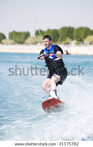 A wakeboarder enjoying the action of riding the wake of the boat.