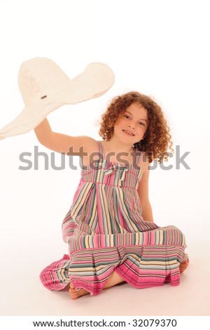 An adorable little girl with very curly hair, playing with a hat