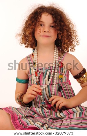 An adorable little girl with very curly hair, playing with costume jewelery.