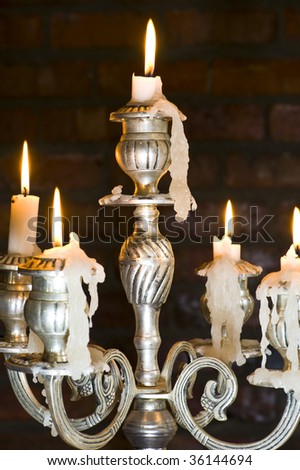 Candles in a chandelier with some melted wax forming stalactites.