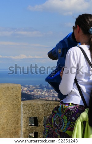Woman looking at the city of Barcelona from Tibidabo, using a coin operated pair of binoculars.