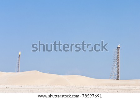 A candle tower burning off excess gas at an oil refinery in the desert.