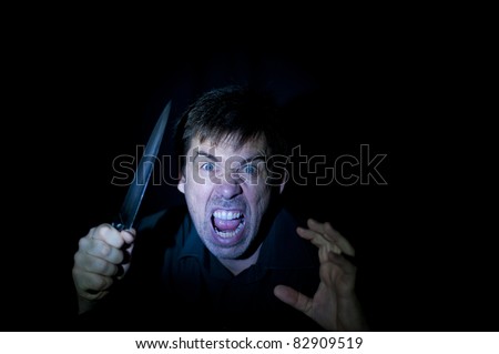 A crazy person with angry expression wielding a knife, on a black background.