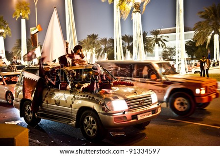 DOHA-DEC 18: Qataris with flags sit or stand on a vehicle during a parade to celebrate their National Day, on December 18, 2011 in Doha, Qatar.  This has been an annual event since 2009.