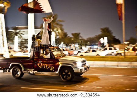 DOHA-DEC 18: Qataris with flags sit or stand on a vehicle during a parade to celebrate their National Day, on December 18, 2011 in Doha, Qatar.  This has been an annual event since 2009.