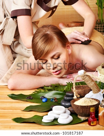 Woman getting stone massage in spa . Still life in the foreground.