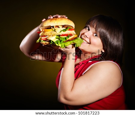 Overweight woman eating hamburger.