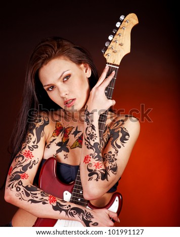 Aggressive young woman with tattoo playing guitar.