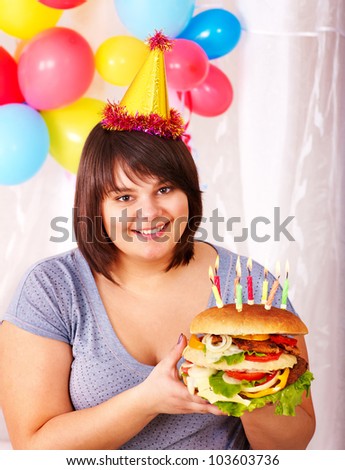 Overweight woman eating hamburger at birthday. Isolated.