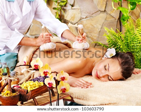 Woman getting thai herbal compress massage in spa.