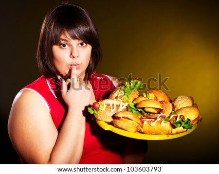 Overweight woman eating hamburger.