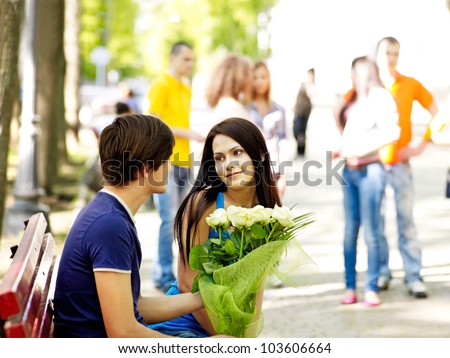 Couple of teenager on date outdoor. Group of people in background.