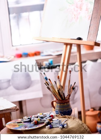 Authentic paint brushes still life on table in art class school as drawing course. Cropped shot of group of brush in clay jar. Discounts on goods for artists. Easel for still lifes.