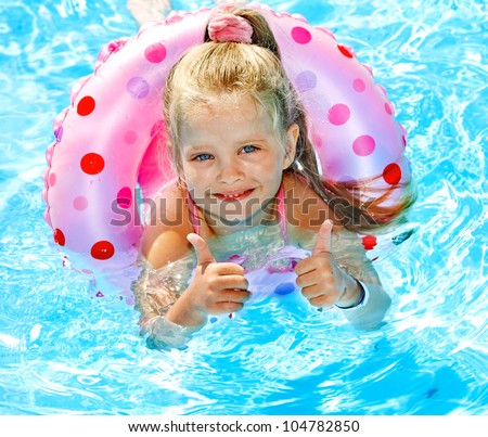 Little girl sitting on inflatable ring in swimming pool.