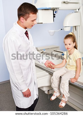 Child patient  in x-ray room looking at doctor.