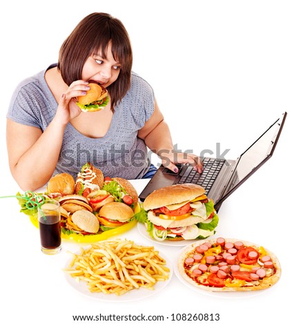Woman eating fast food at working pc. Isolated.