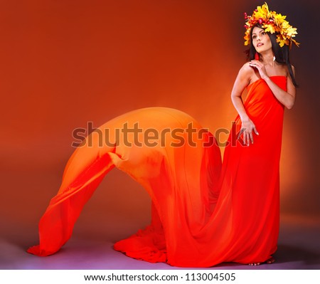 Girl with wreath of autumn leaves and orange dress. Art photo.