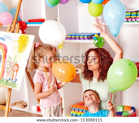 Child with teacher inflating balloons in school.