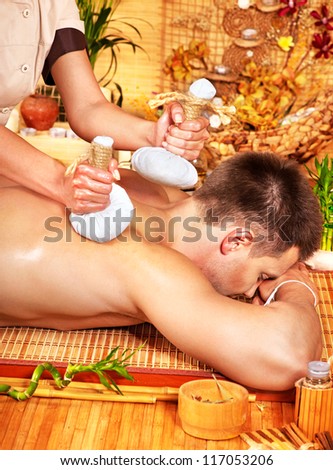 Man getting herbal ball massage treatments  in spa.