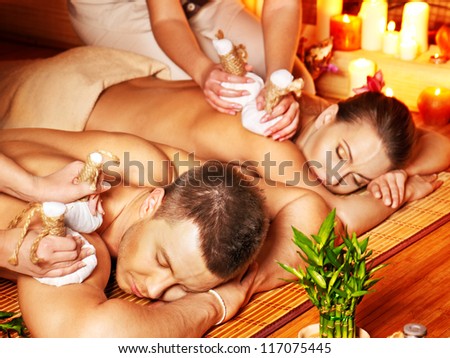 Man and woman getting herbal ball massage in bamboo spa.
