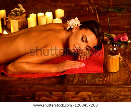 Ayurveda massage of woman in spa salon. Girl on candles background in spa salon. Luxary interior in oriental therapy .