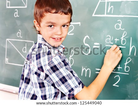 Teen school child near blackboard  in classroom.