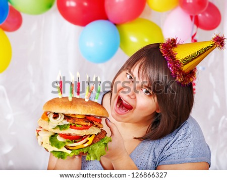 Woman eating hamburger at birthday at home.