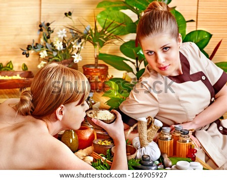 Woman getting stone therapy massage in bamboo spa.
