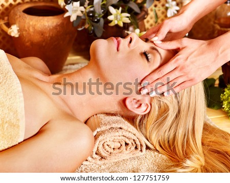 Woman getting facial massage in tropical spa.