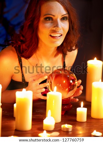 Woman holding scrying ball and candle.