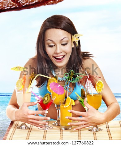 Happy girl in bikini on beach drinking cocktail.