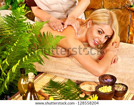 Woman getting back massage in tropical spa.