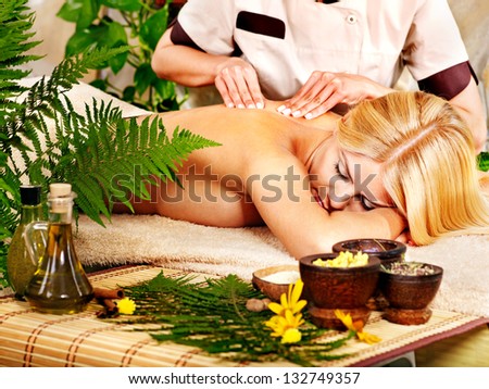 Woman getting back massage in tropical spa.