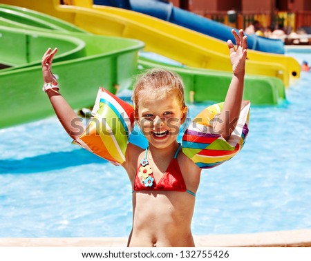 Child with armbands playing in swimming pool. Summer outdoor.