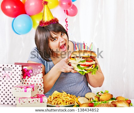 Woman eating hamburger at birthday. Isolated.