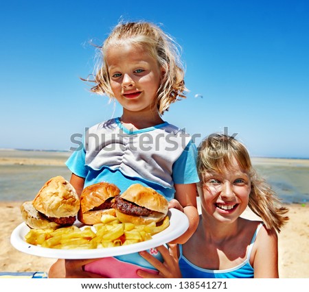 Child eating fast food at beach outdoor.