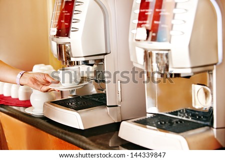 Coffee machine with female hand and cup of coffee.