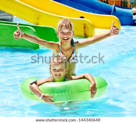 Children sitting on inflatable ring in swimming pool.