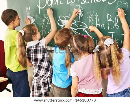 Children writing on blackboard at school.