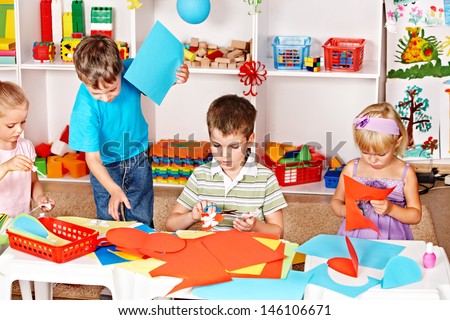Child boy cutting out scissors paper in preschool.