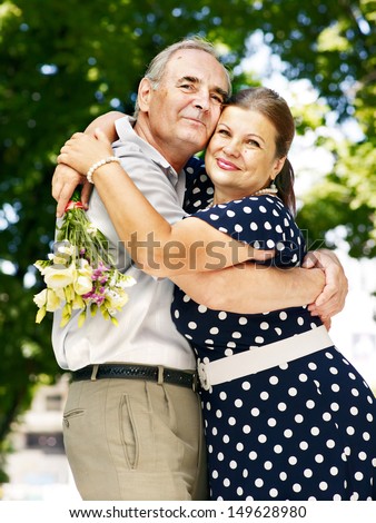 Happy old couple with flower outdoor.