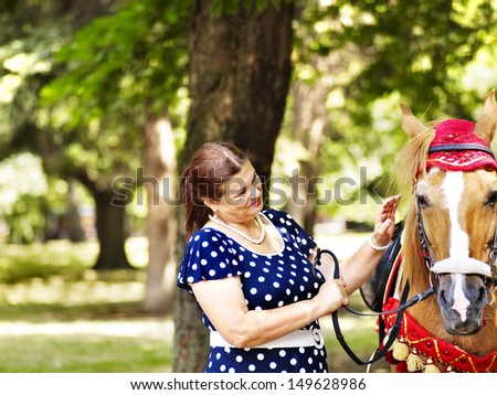 Happy old woman horseback riding outdoor.