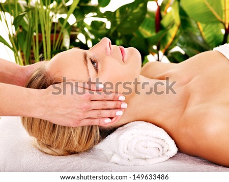 Woman getting facial massage in tropical beauty spa.