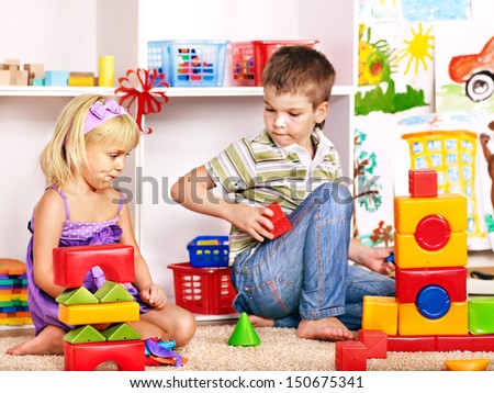 Little boy and girl in kindergarten stacking block.