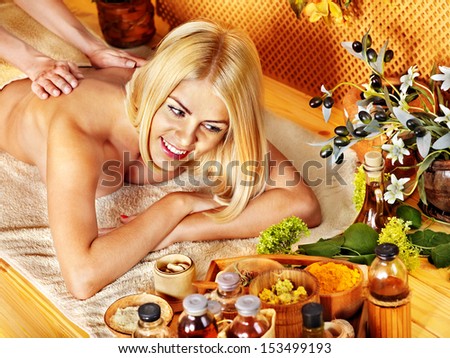 Blond woman getting massage in tropical spa.