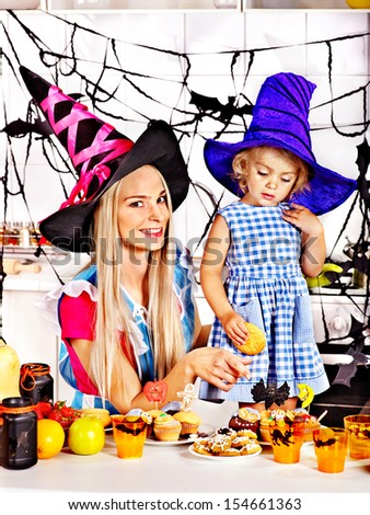 Mother with daughter preparing halloween cake.