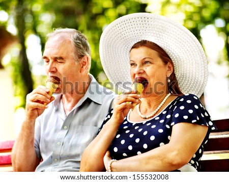 Happy old couple eating ice-cream outdoor.